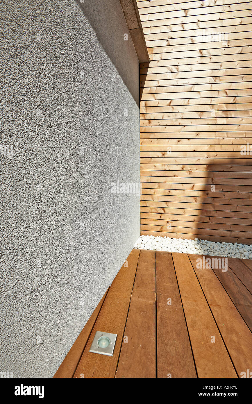 Mur de ciment blanc rénové et d'isolation de bardage bois dans une cour Banque D'Images