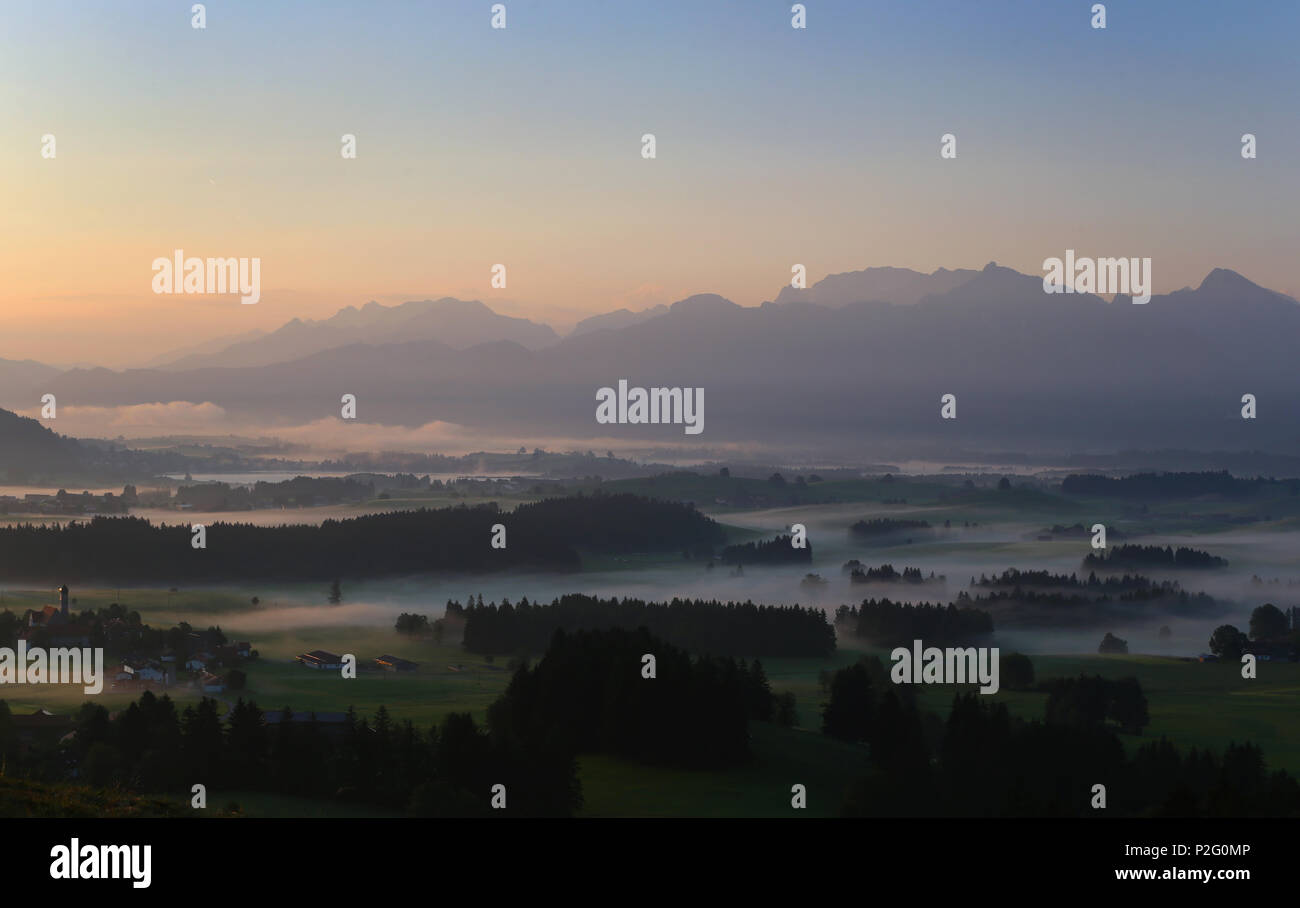 15 juin 2018, l'Allemagne, l'Eisenberg : matin le brouillard entourant l'église de pèlerinage de Maria-Hilf avant le panorama exprimés par les Alpes au lever du soleil. Photo : Karl-Josef Opim/dpa Banque D'Images