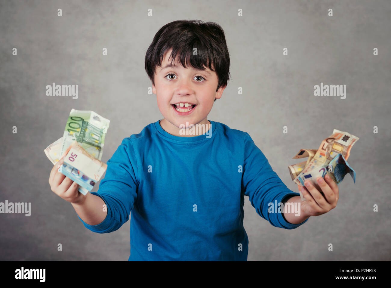 Smiling boy with euro bills sur fond gris Banque D'Images