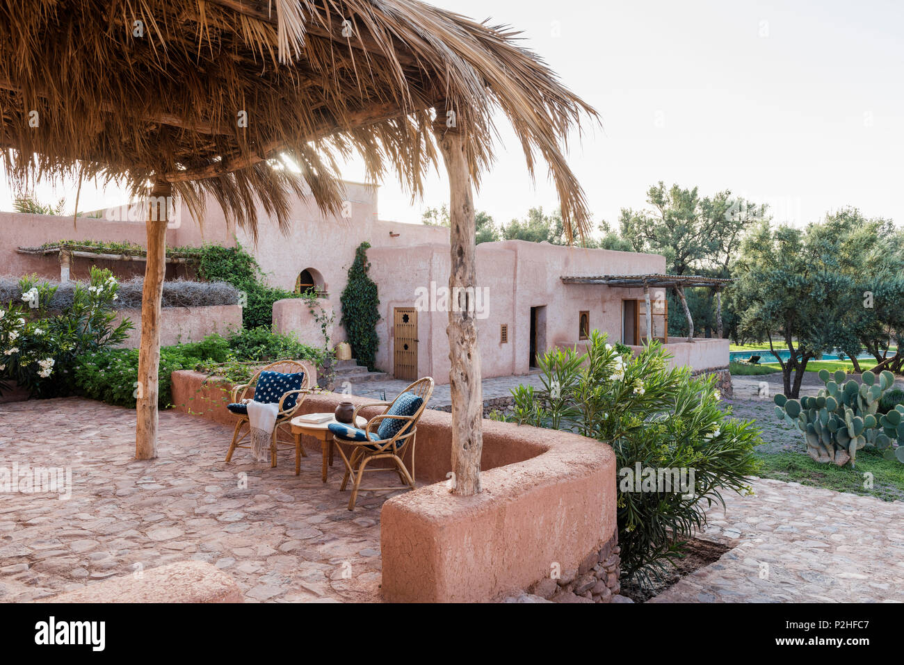 Une paire de chaises en rotin sur la terrasse du jardin avec des murs de terre, les herbes et plantes sauvages. marocain Jardin design by Arnaud Casaus Banque D'Images