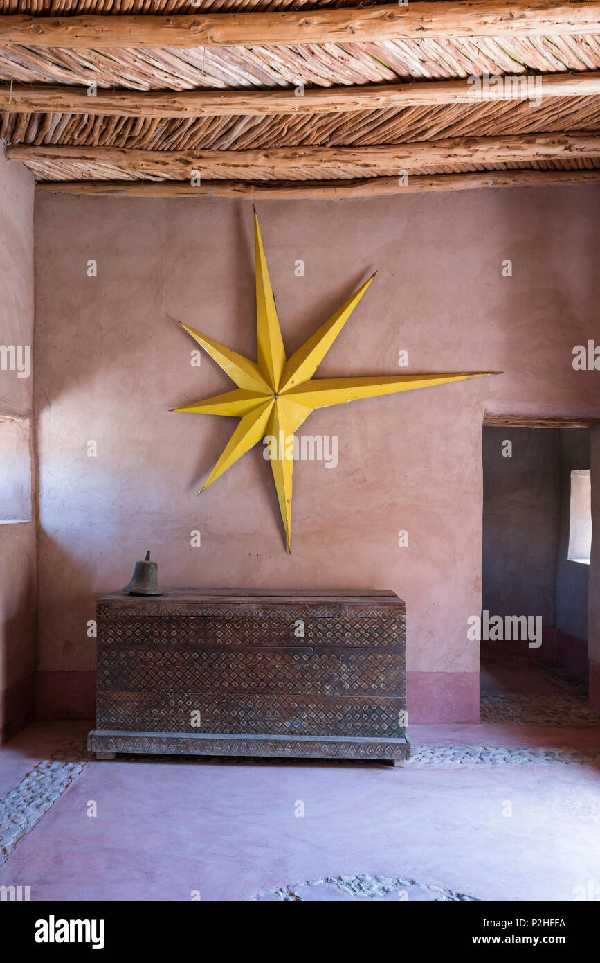 Grande étoile jaune accroché sur la paroi de la terre dans la région de hall d'entrée d'une maison berbère avec des meubles anciens en bois et de lambris de poitrine porte cloutée Banque D'Images