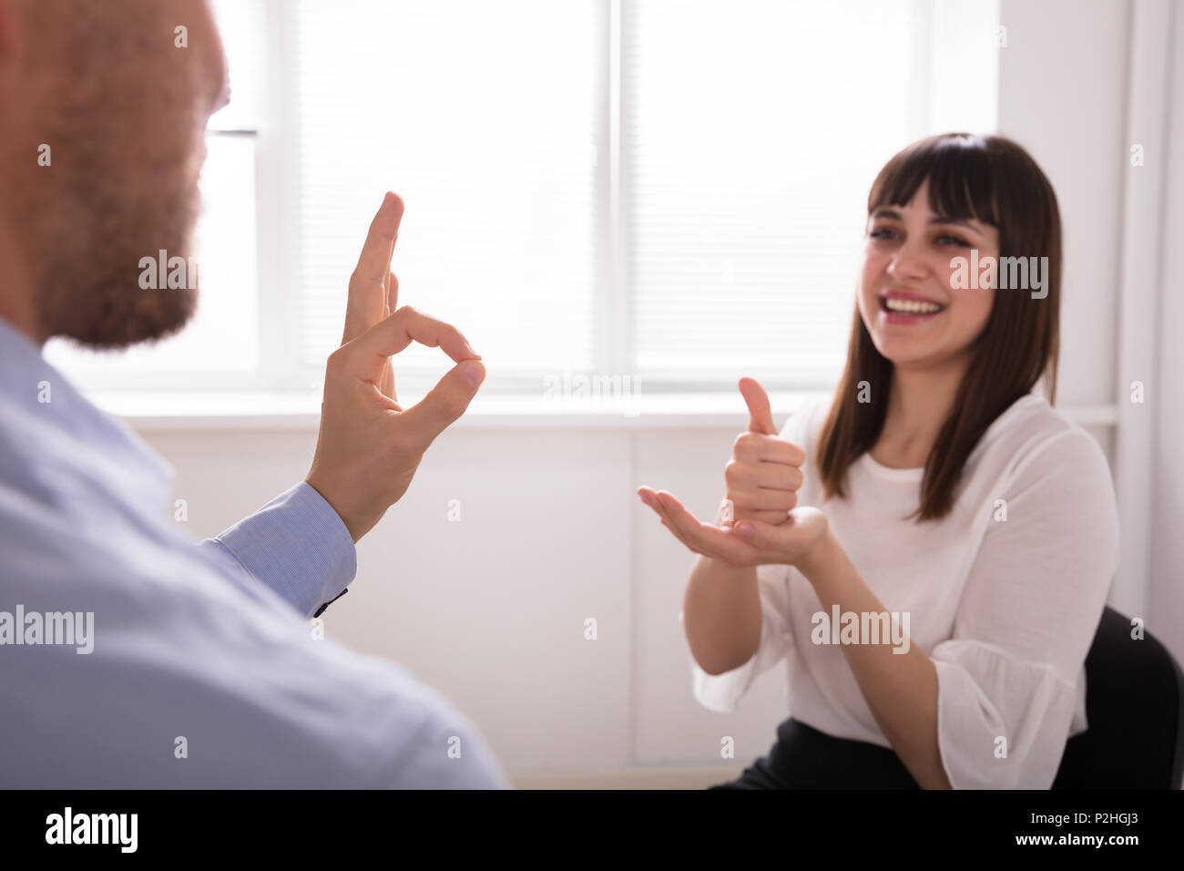 Souriante jeune femme et l'homme parle avec la langue des signes sur fond blanc Banque D'Images