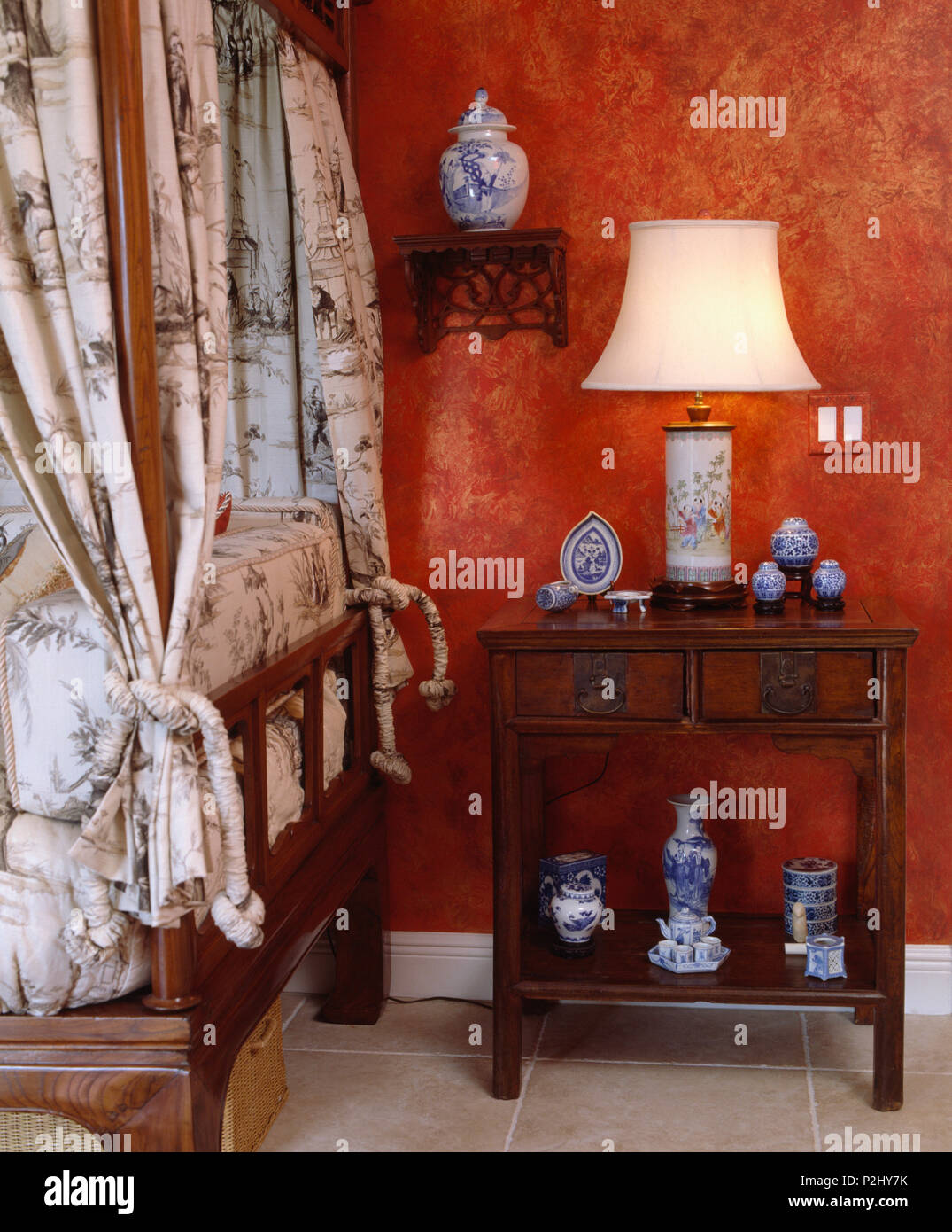 Lampe allumée sur l'acajou table de chevet dans une chambre traditionnelle  avec papier peint rouge et blanc +bleu vases de style chinois Photo Stock -  Alamy