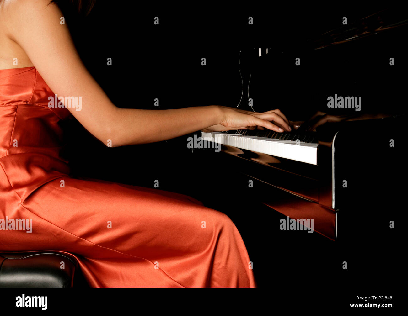 Jeune femme jouant du piano dans un concert d'or dress Banque D'Images