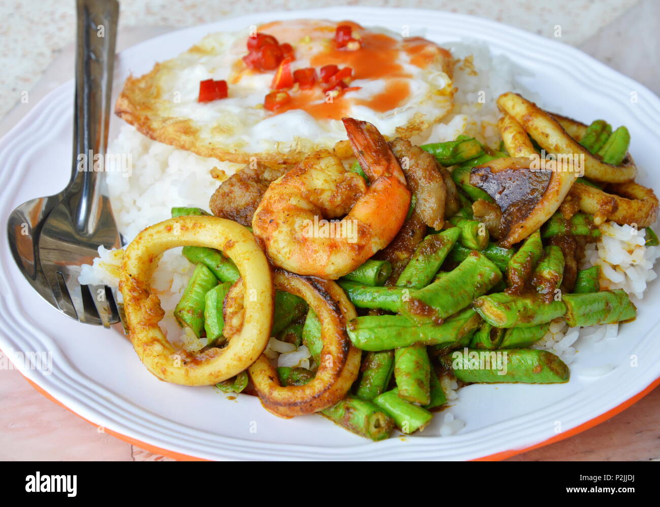 Sauté de fruits de mer au curry et œuf frit sur le riz Banque D'Images