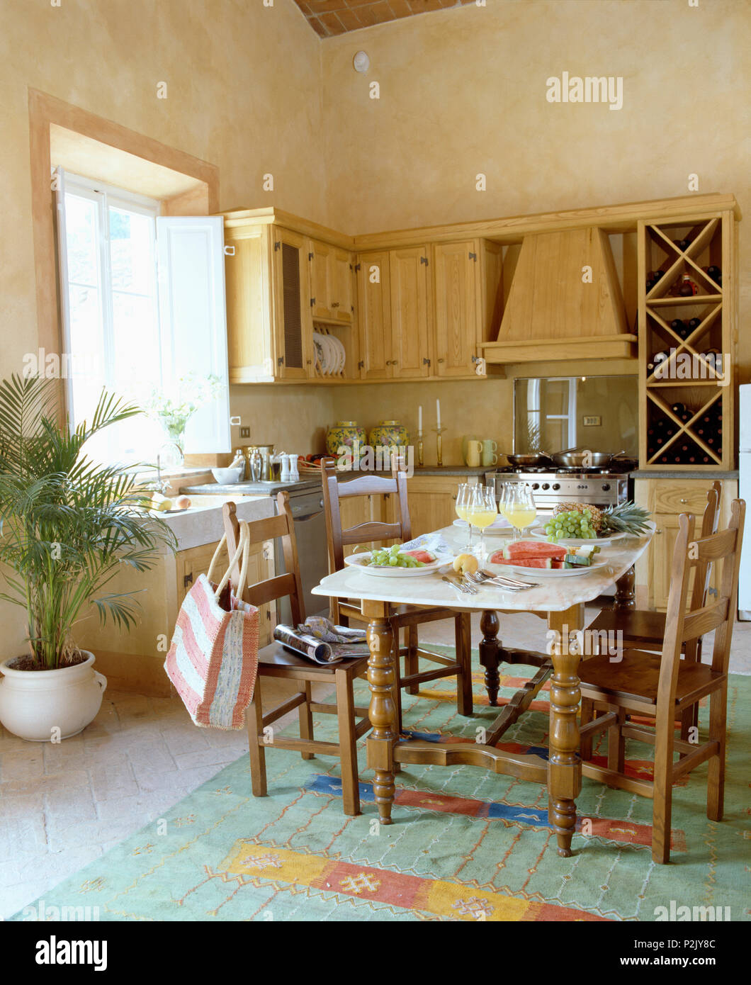 Chaises en bois rustique au set de table pour le déjeuner dans la cuisine  toscane avec lavabo à côté de potted palm Photo Stock - Alamy