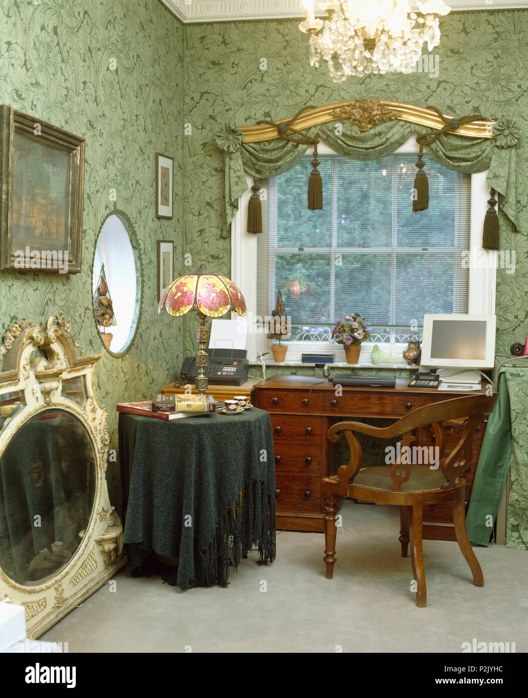 De style Tiffany lampe en verre sur la table avec un chiffon en chenille verte à côté d'un bureau ancien et chaise dans fashiioned avec étude de vieux papier peint vert Banque D'Images