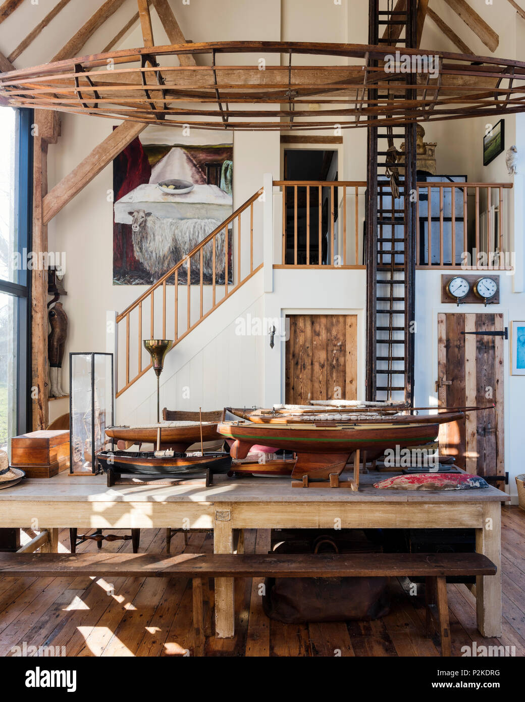 Salle à manger avec double hauteur 1940 fire modèle échelle et coques de navires avec de vieux châssis en canot dans le Sussex grange convertie Banque D'Images