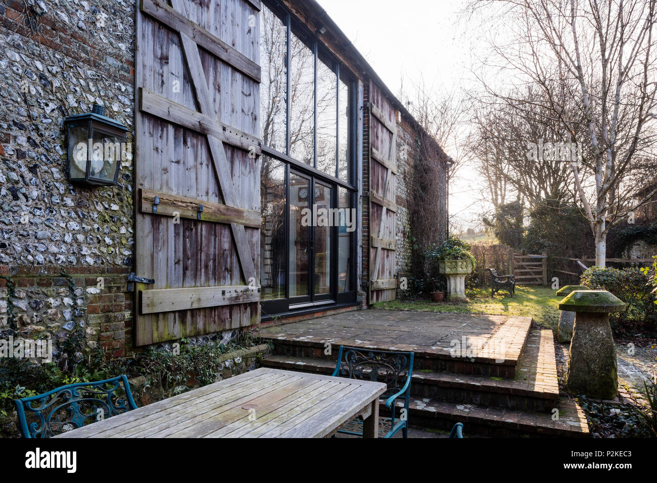 Salon de jardin sur terrasse de barn convesrion avec de grandes fenêtres et volets bois, Sussex Banque D'Images