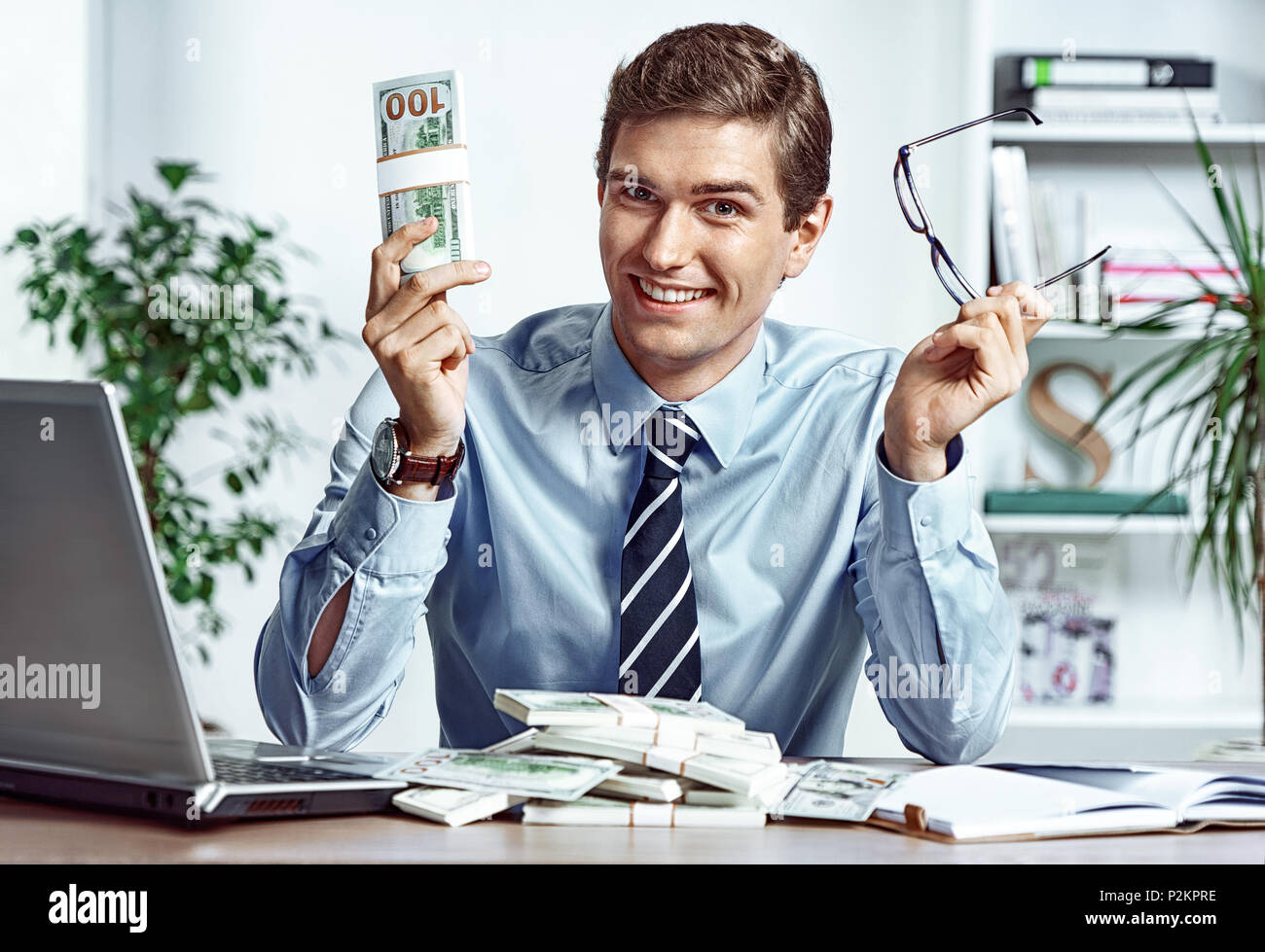 Homme d'affaires réussi enlève ses lunettes et montrant l'argent. Photo de jeune homme travaillant dans le bureau. Concept d'affaires Banque D'Images