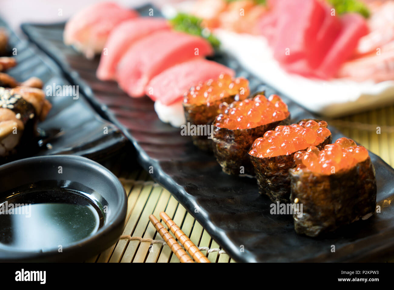 Sushi avec des baguettes et de la sauce de soja. Sushi roll Japanese food in restaurant. Sushi oeufs de saumon avec saumon, légumes, oeufs de poisson volant et de caviar Banque D'Images
