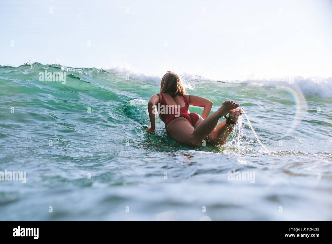 Vue arrière de la femme en costume de bain surf seul dans ocean Banque D'Images