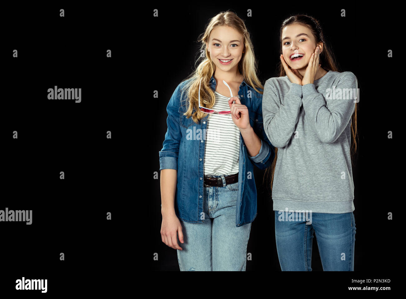 Happy teen girls looking at camera isolated on black Banque D'Images