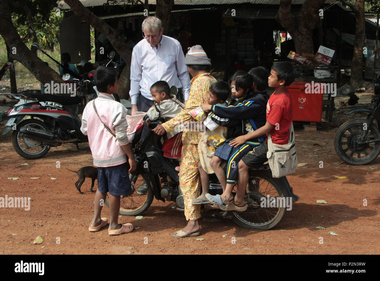 Une moto avec six personnes sur il prend les enfants de l'école. M. Conor Gilligan, l'un des collecteurs de fonds, les regarde. Rame à l'école, au Cambodge. Banque D'Images