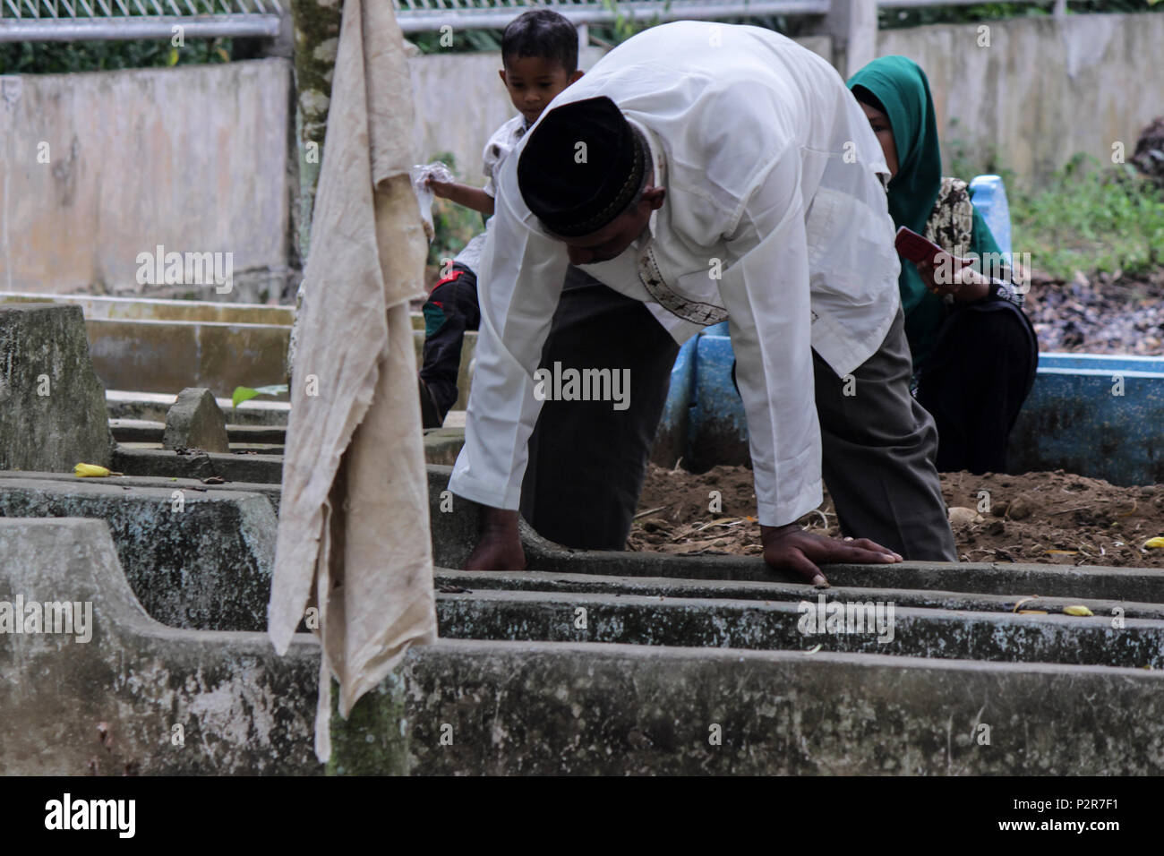 Un musulman vu à la recherche sur un parent tombe pendant le pèlerinage. Les musulmans vu de leurs proches tombe, lors d'un pèlerinage au cimetière public à Lhokseumawe Ville. La plupart des musulmans à Aceh déjà fait le dernier pèlerinage grave avant d'entrer dans le mois sacré du Ramadan et le jour de l'Aïd al-Fitr, à prier pour les familles de ceux qui sont morts. Banque D'Images