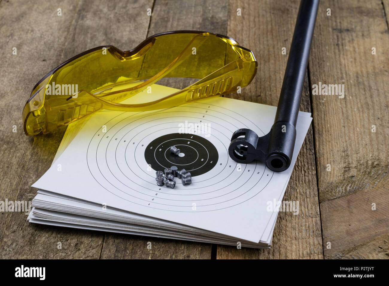 Arme de tir et pneumatique. Bouclier et hits avec balles de plomb sur une table en bois. Fond sombre. Banque D'Images