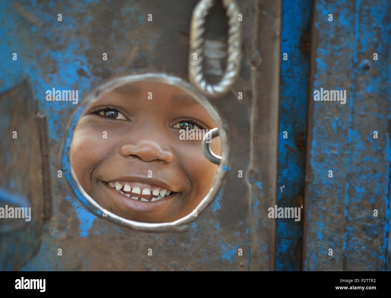 Un de ses pairs par un trou dans la porte autour d'un composé de l'église au milieu d'un camp pour plus de 5 000 personnes déplacées à Riimenze, au Soudan du Sud. Banque D'Images