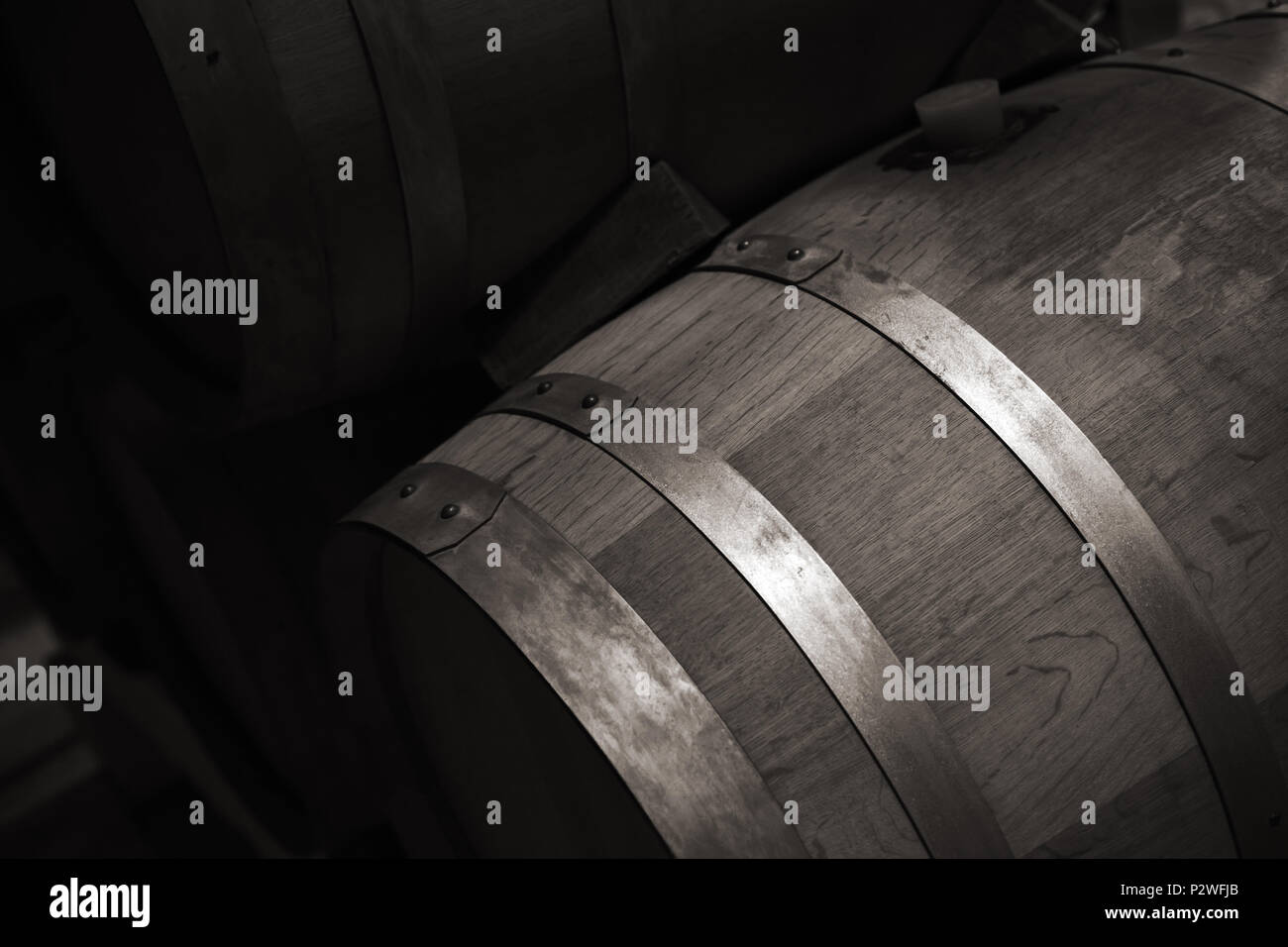 Tonneau en bois avec du vin rouge dans l'obscurité winery, Close up photo monochrome avec selective focus Banque D'Images