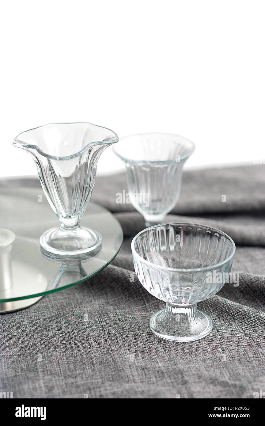 3 bols en verre propre pour la crème glacée, avec différentes textures, sont sur la table avec une nappe gris Banque D'Images