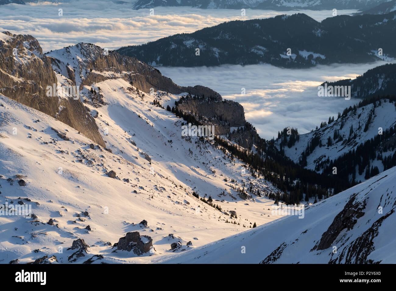 Du côté de la montagne couverte de neige pendant un nuage rare-inversion du haut des Alpes, éclairé par le soleil du soir. Banque D'Images