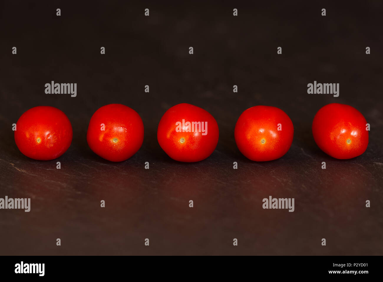 Tomates italiennes bébé rouge isolé sur un fond sombre sur une surface en ardoise. Concept de saine alimentation Fruits Banque D'Images