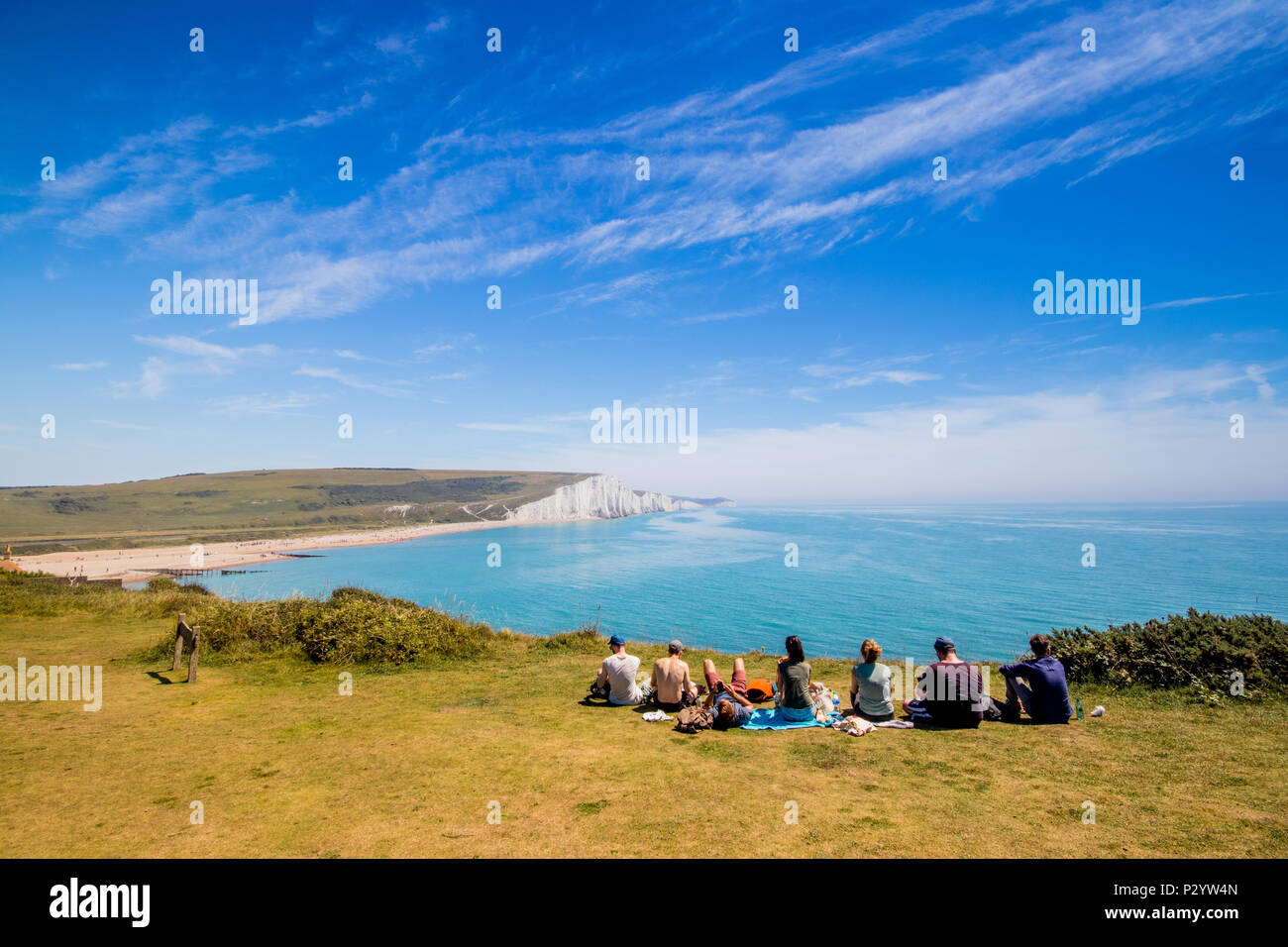 Les promeneurs assis au bord de la falaise en direction de Cuckmere Haven, sept Sœurs Country Park près de Eastbourne, East Sussex, UK Banque D'Images