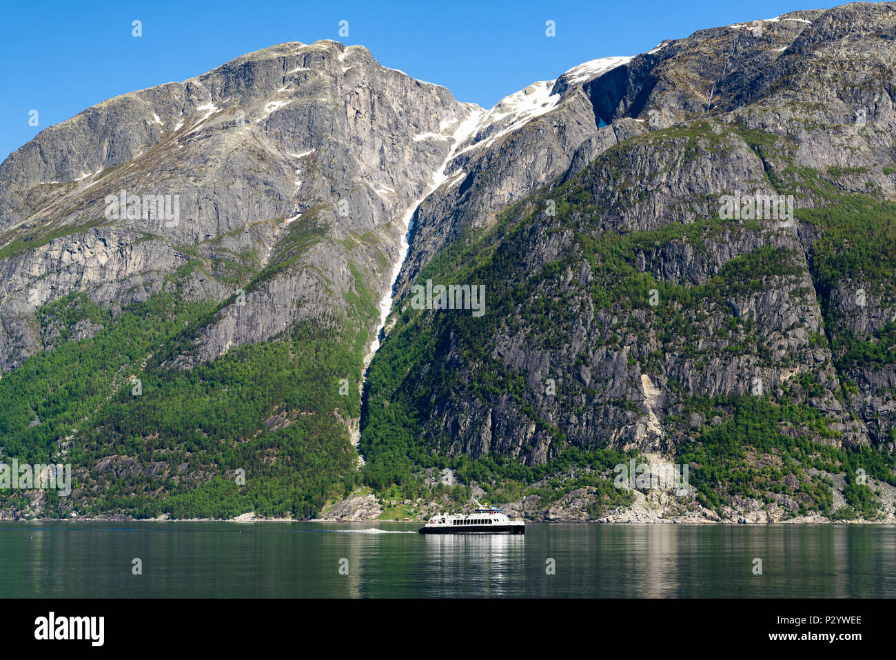 Petit tour en bateau ou en ferry dans un fjord sur une journée ensoleillée. Des pics de montagne de neige et de glace à l'arrière-plan. Location Eidfjord en Hordaland, Norvège. Banque D'Images