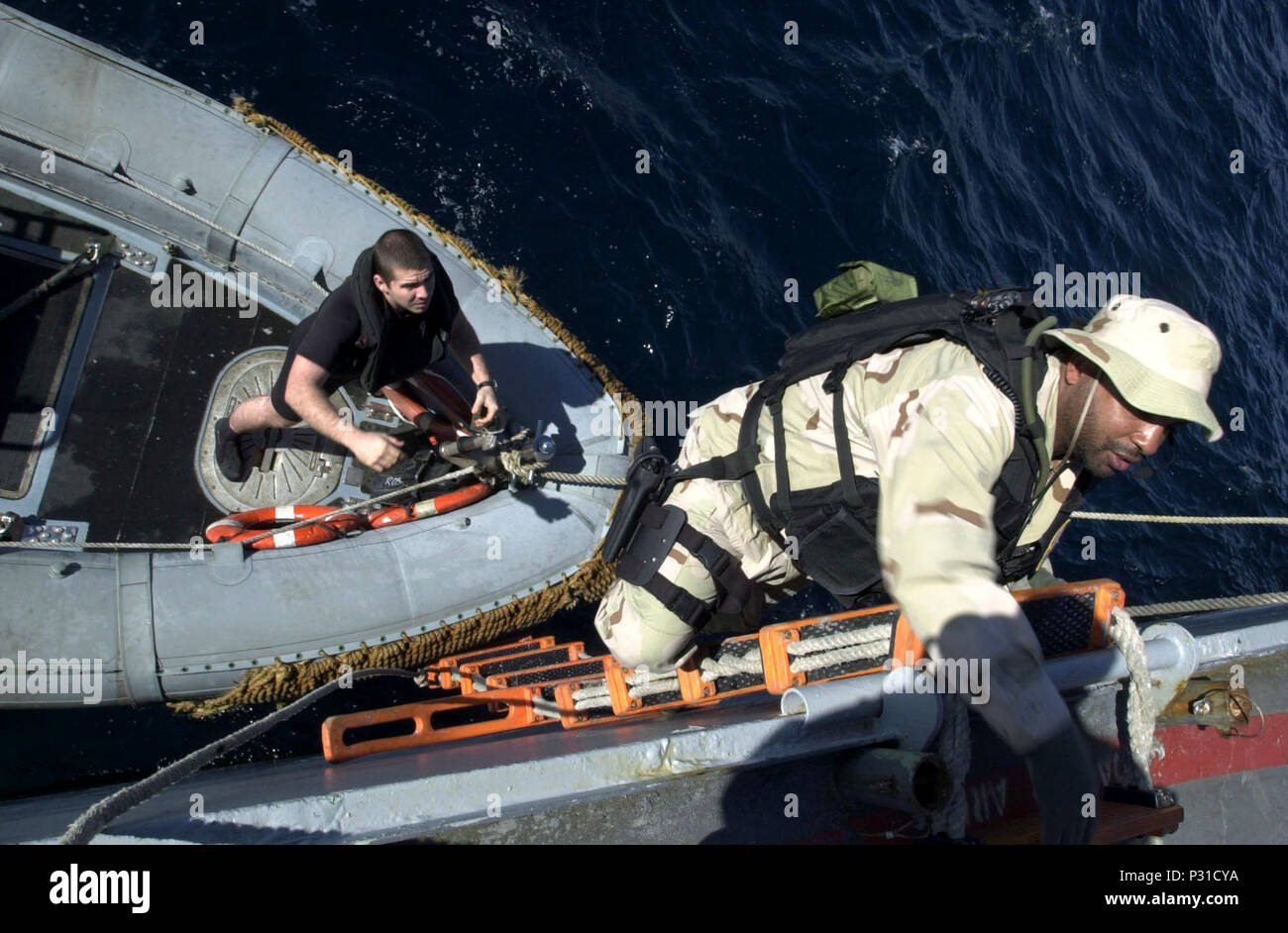 À bord de mer USS Lake Champlain (CG 57) 15 janvier 2001 -- un membre de l'arraisonnement Perquisition et saisie (VBSS) de l'équipe à bord de l'USS Lake Champlain boards le canot pneumatique à coque rigide (RHIB) qui va le prendre et l'équipe de VBSS un navire marchand en attente d'embarquement. Les opérations d'interception maritime (MIO) sont menées par les Banque D'Images