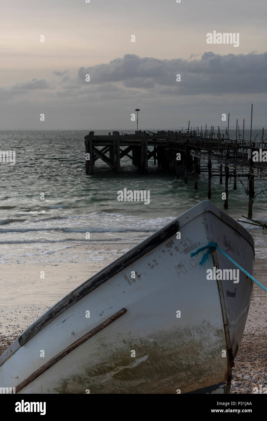 Une belle scène côtière et de l'atmosphère à totland bay sur l'île de Wight avec un vieux bateau en premier plan au coucher du soleil.atmosphère Ile de Wight. Banque D'Images