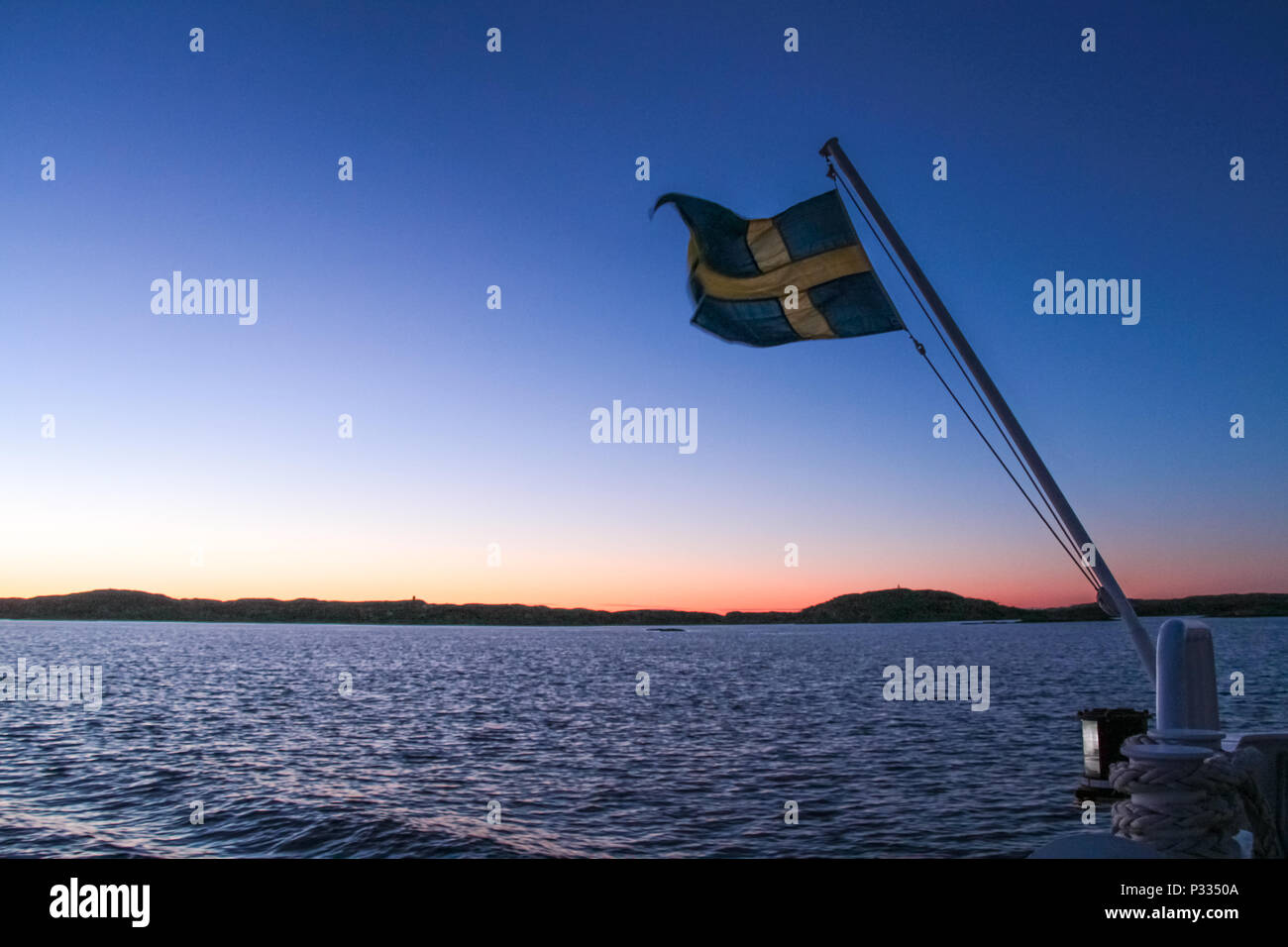 La Suède drapeau sur un voile de pourpre et le coucher du soleil en mer silhouette de montagne Banque D'Images