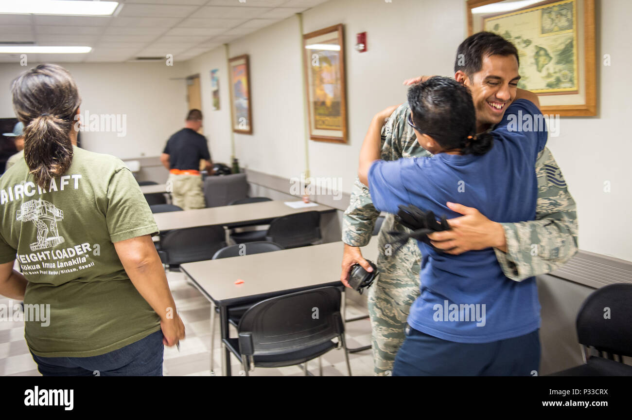 Puis Tech. Le Sgt. Alfred Van Gieson, maintenant Maître sergent, est embrassé par les co-travailleurs Agapay Kalei, un gestionnaire spécial, et Luis Ululant, gauche, un planificateur de charge dans la salle de pause du 48e Escadron de Port Aérien, 624th groupe de soutien régional, d'une base commune Pearl Harbor-Hickam, Oahu, Hawaii, 13 août 2016. Van Gieson, réserviste de l'Armée de l'air, est un vétéran de l'opération Iraqi Freedom, un champion du monde de balancier, ou Va'a, pagayeur a reçu une formation en byLuis chargement de l'aéronef lorsque les deux ont travaillé pour l'Aloha Airlines. (U.S. Air Force photo par J.M. Eddins Jr.) Banque D'Images