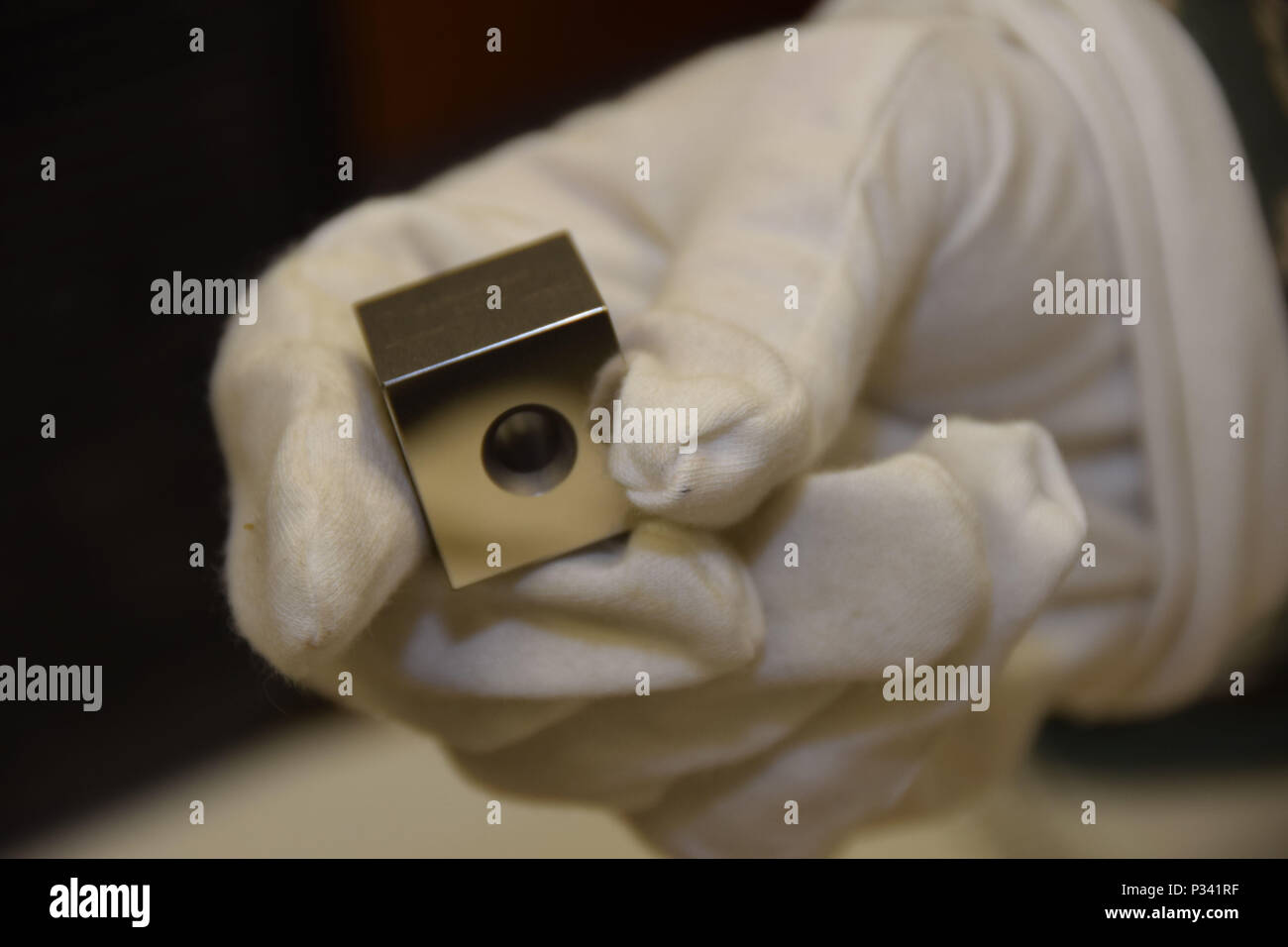 La main droite gantée de sergent. Jacob Lober, 379e Escadron de maintenance expéditionnaire expéditionnaires de l'équipement de mesure de précision, artisan de laboratoire traite un bloc de jauge d'acier le 24 août 2016, Al Udeid Air Base, au Qatar. Le bloc pourrait être utilisée pour l'étalonnage d'un micromètre, étriers ou quoi que ce soit qui ont une longueur de l'étalonnage. (U.S. Photo de l'Armée de l'air technique/Sgt. CarlosJ. Treviño/libérés) Banque D'Images