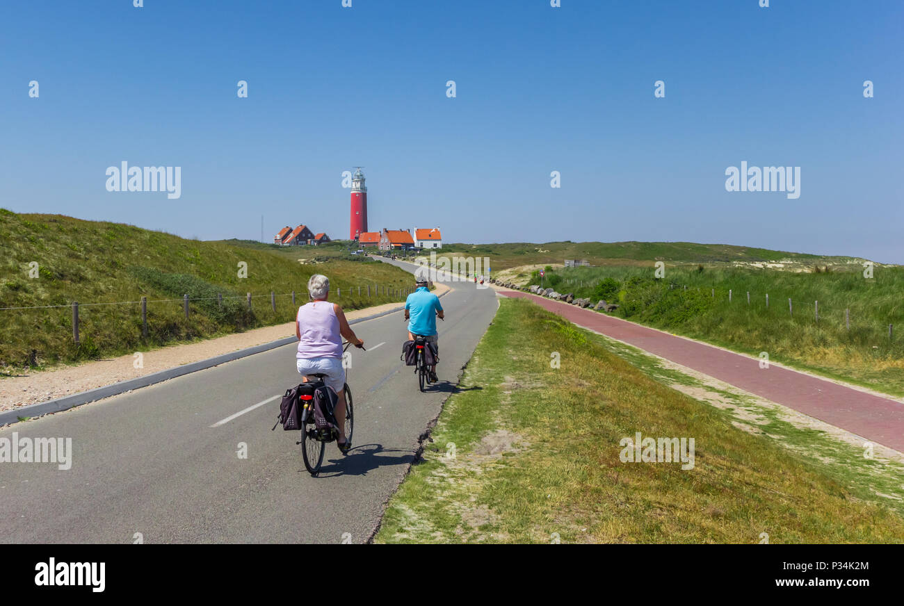 Couple riding leurs bicyclettes au phare sur l'île de Texel, Pays-Bas Banque D'Images