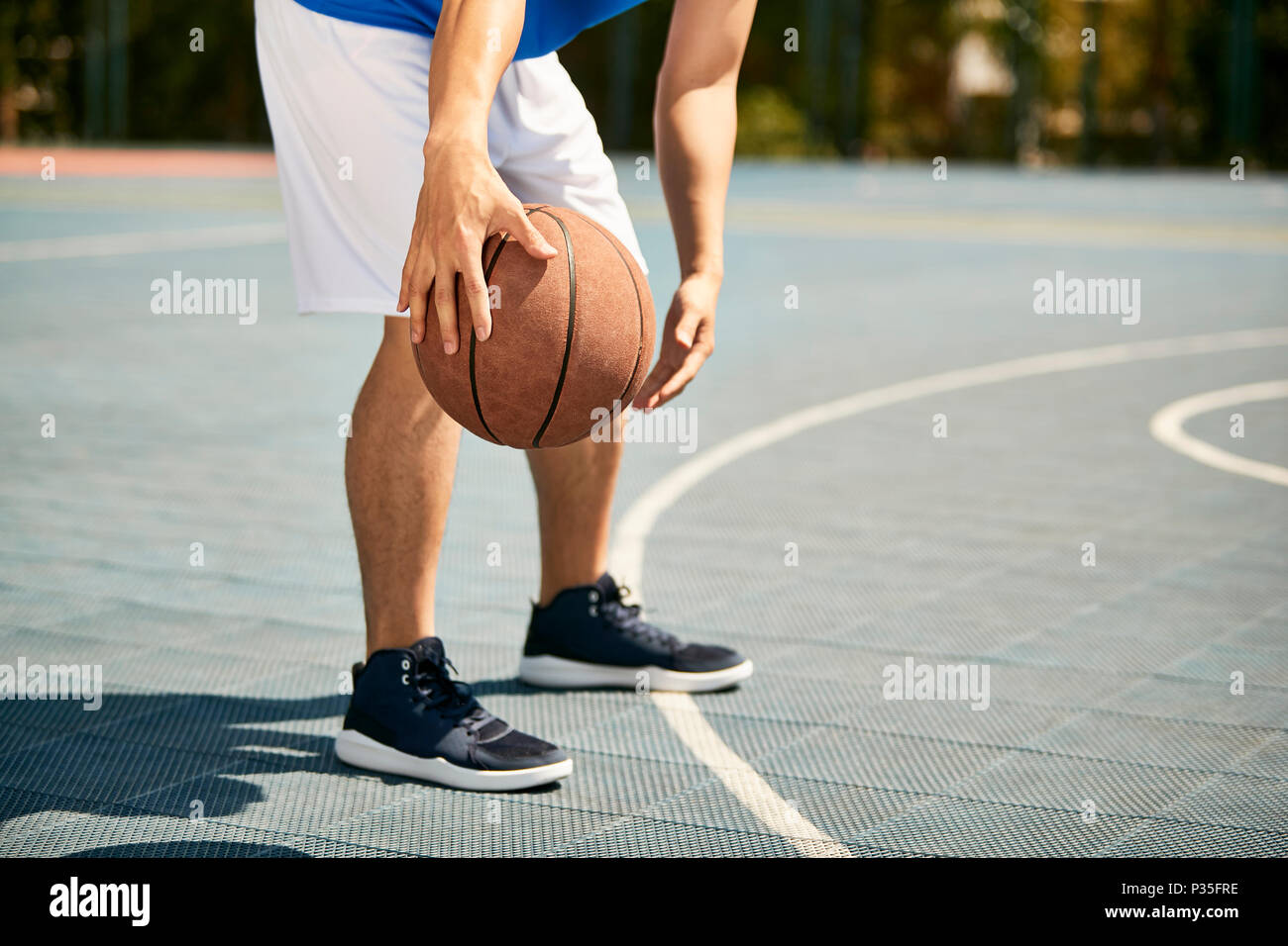 Les jeunes mâles d'Asie de basket-ball dribble et pratique de maniement du ballon habileté sur cour. Banque D'Images