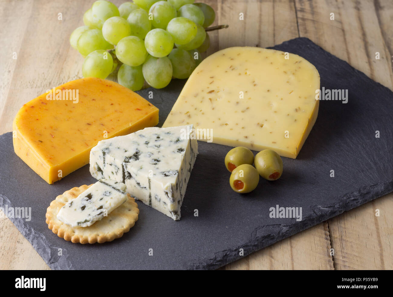 Plateau de fromages aux trois fromages Gouda, avec pimento, gouda avec les graines de cumin et fromage bleu roquefort close up sur fond de bois rustique Banque D'Images