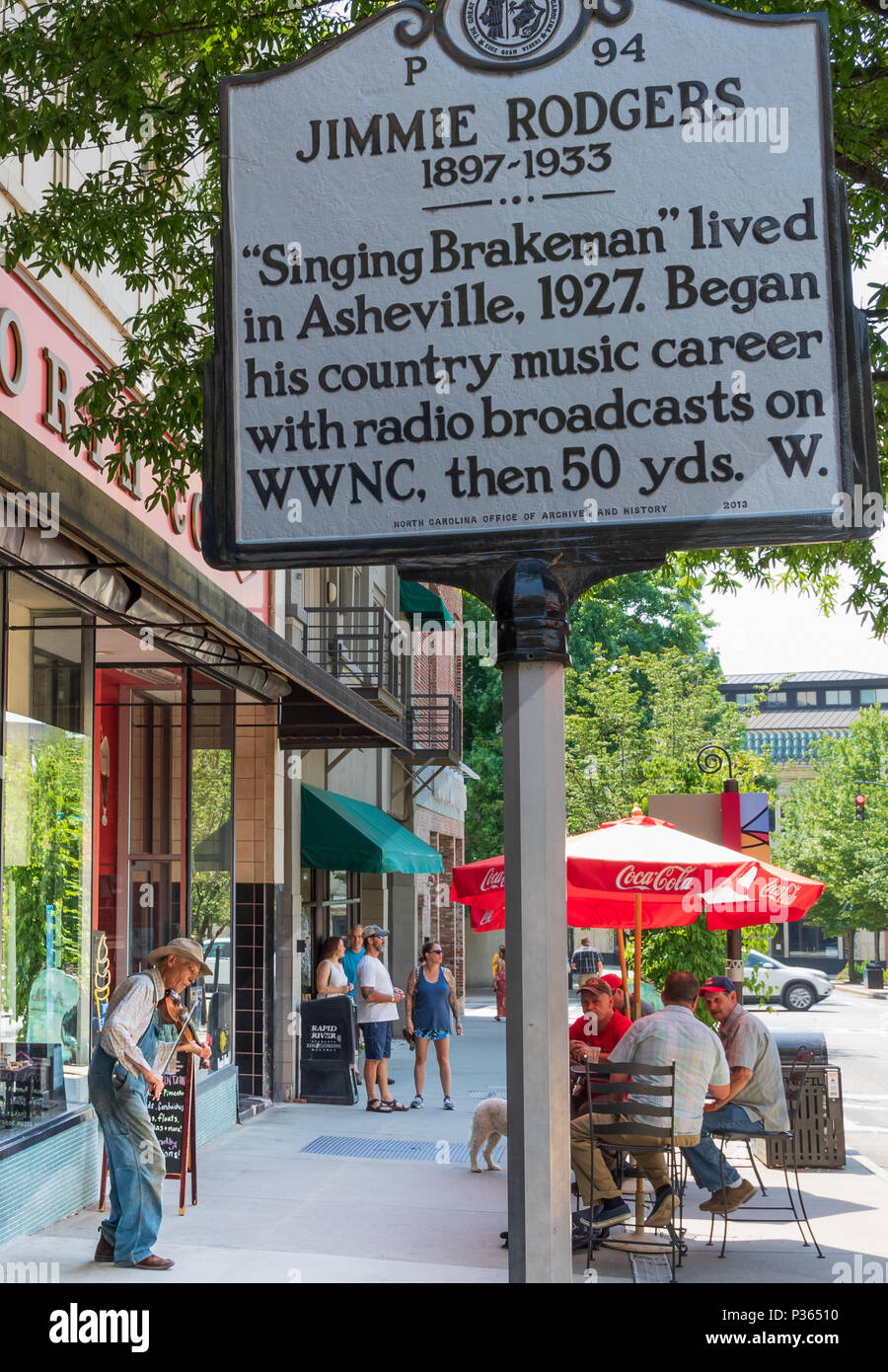 ASHEVILLE, NC, USA-10 le 18 juin : une montagne fiddler joue pour obtenir des conseils sur la rue, sous un panneau commémorant la chanteuse de country Jimmie Rodgers. Banque D'Images
