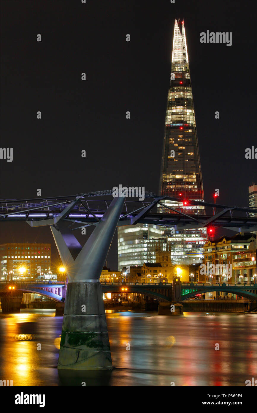 Le Millennium Bridge avec le fragment dans l'arrière-plan pendant la nuit, les lumières de la ville et de la Tamise par des réflexions de la ville sur l'eau. Banque D'Images