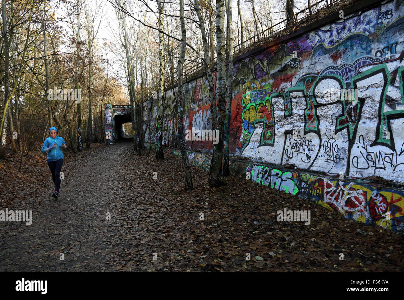 Berlin, Allemagne, woman jogging le long d'un mur jonché de graffiti Banque D'Images