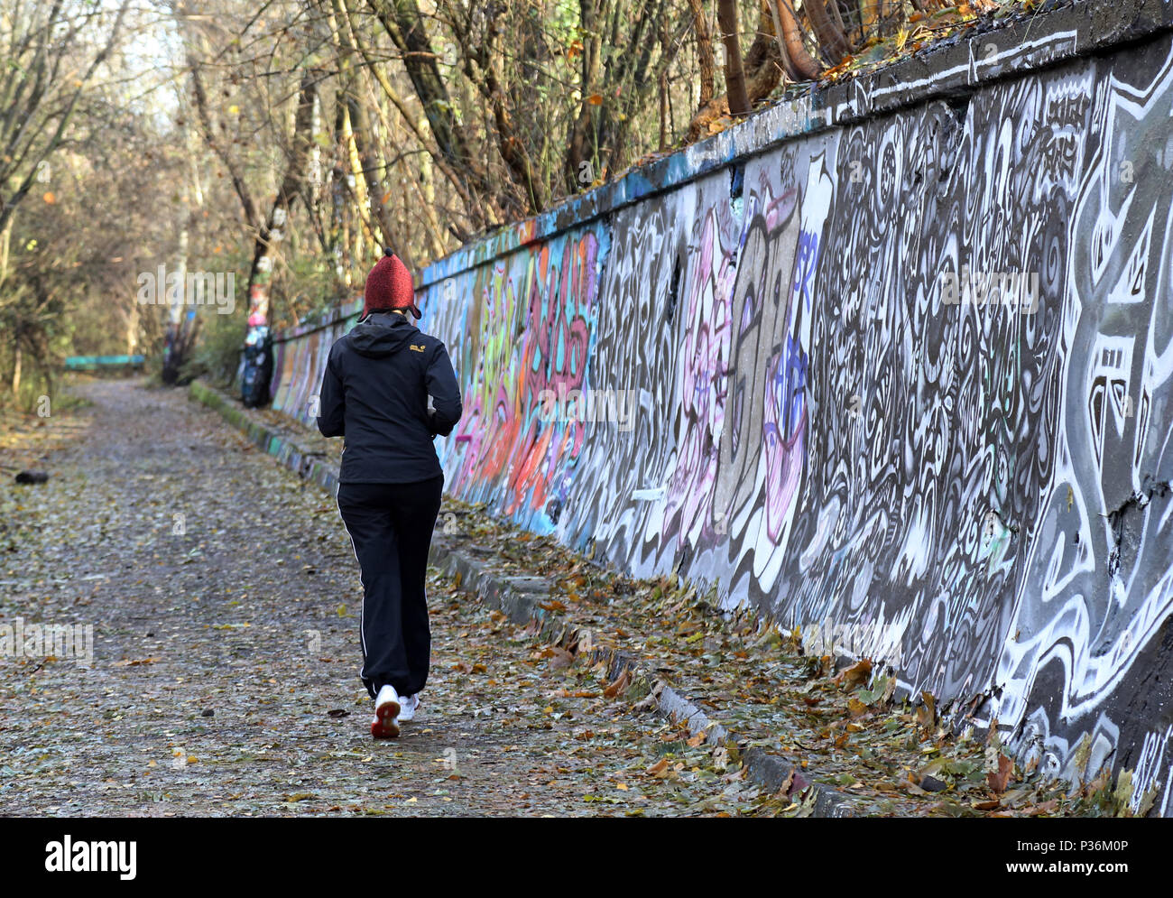 Berlin, Allemagne, woman jogging le long d'un mur jonché de graffiti Banque D'Images