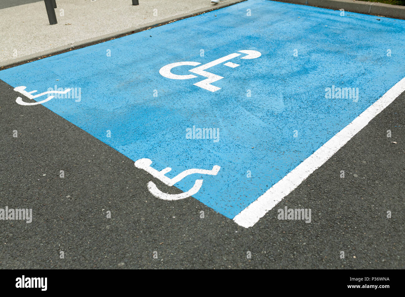 Symbole handicapés International peint en bleu vif sur un centre commercial de parking. L'espace est clairement indiquée sur chaque côté avec d'autres Banque D'Images