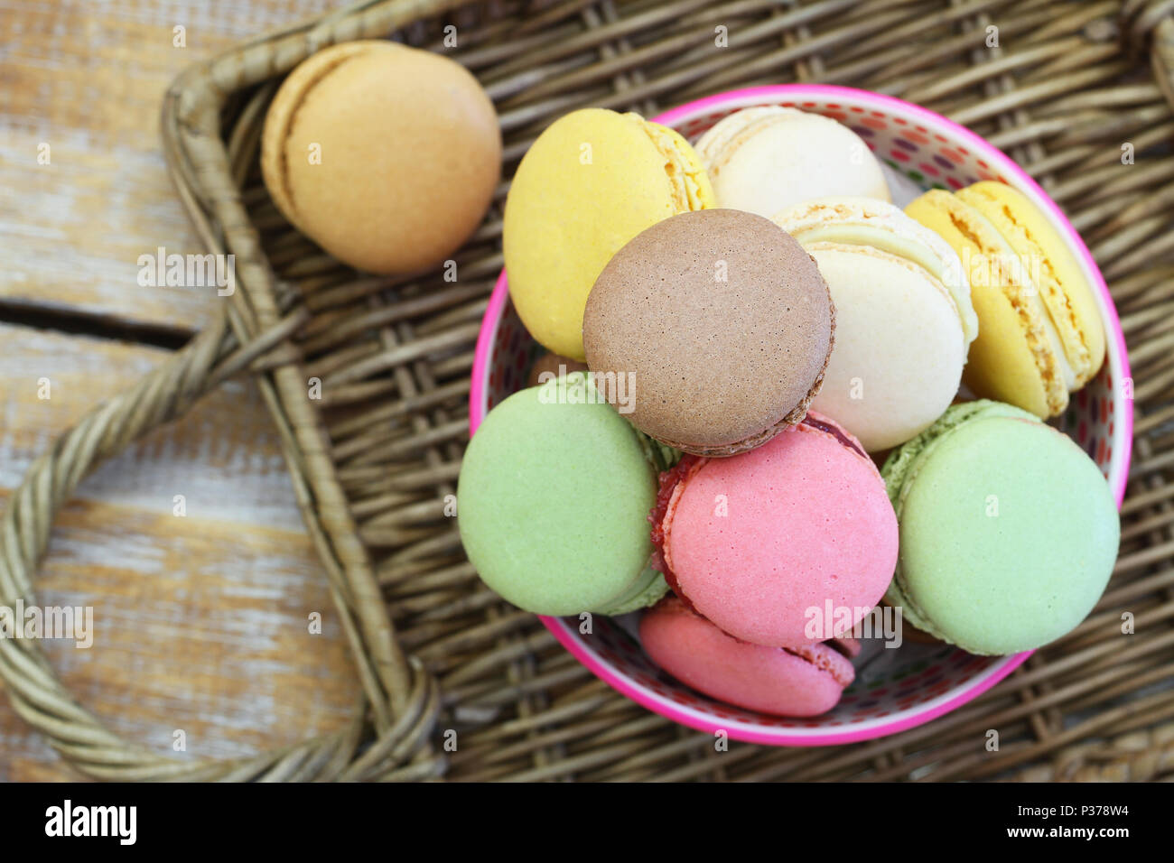Macarons colorés dans un bol sur la surface en osier Banque D'Images