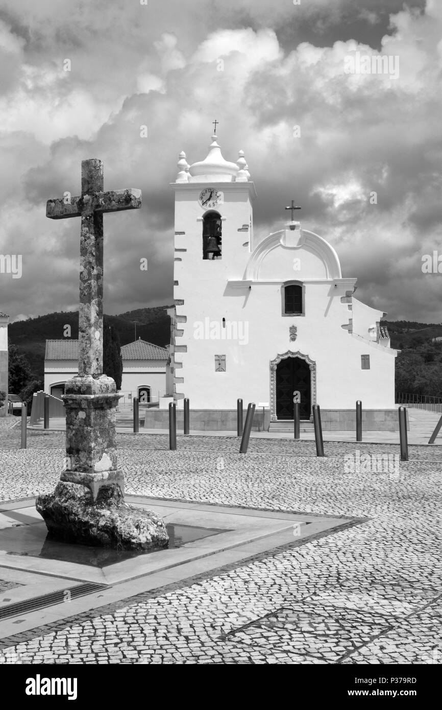 Image en noir et blanc de la croix et de l'église dans la place principale de Querenca, Portugal Banque D'Images