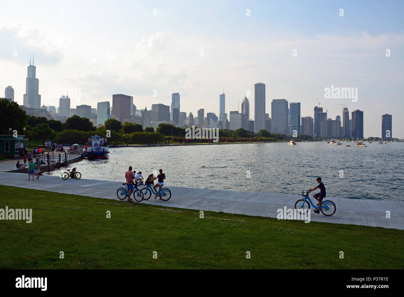 Les visiteurs de Chicago ride vélos partagent le long du lac sur le Museum Campus avec la ville en arrière-plan. Banque D'Images