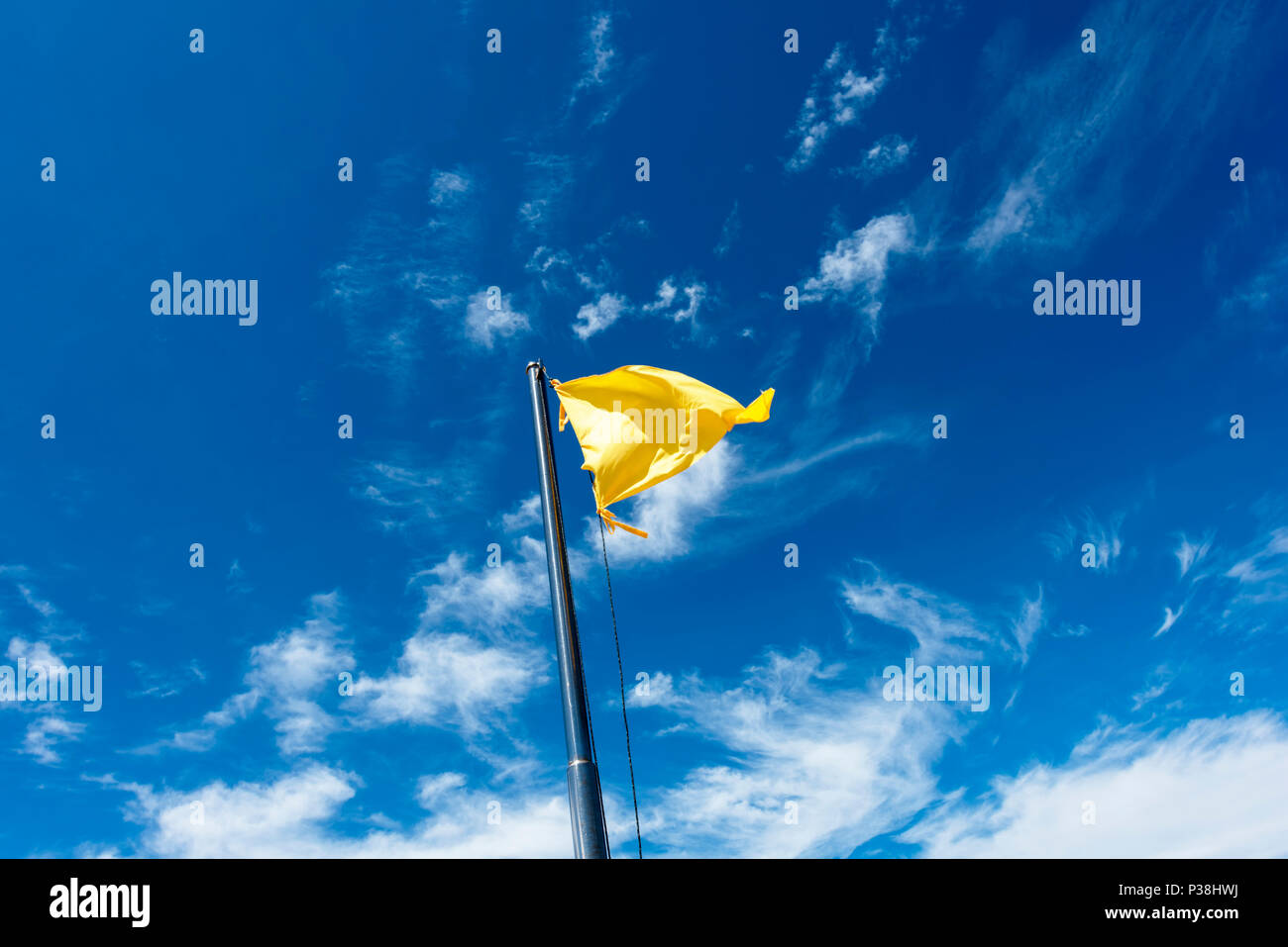 Drapeau jaune sur un poteau, voletant dans la brise contre un ciel bleu à Kota Kinabalu, Bornéo Banque D'Images