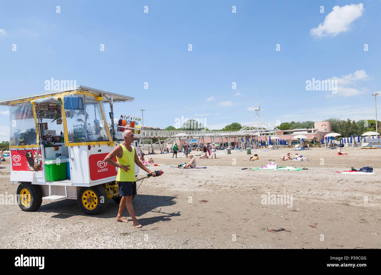 Vendeur tirant un chariot de rafraîchissements avec des glaces et des boissons gazeuses le long d'une plage, Lido di Venezia, Venise, Italie. Blue Moon pier, tour et resta Banque D'Images