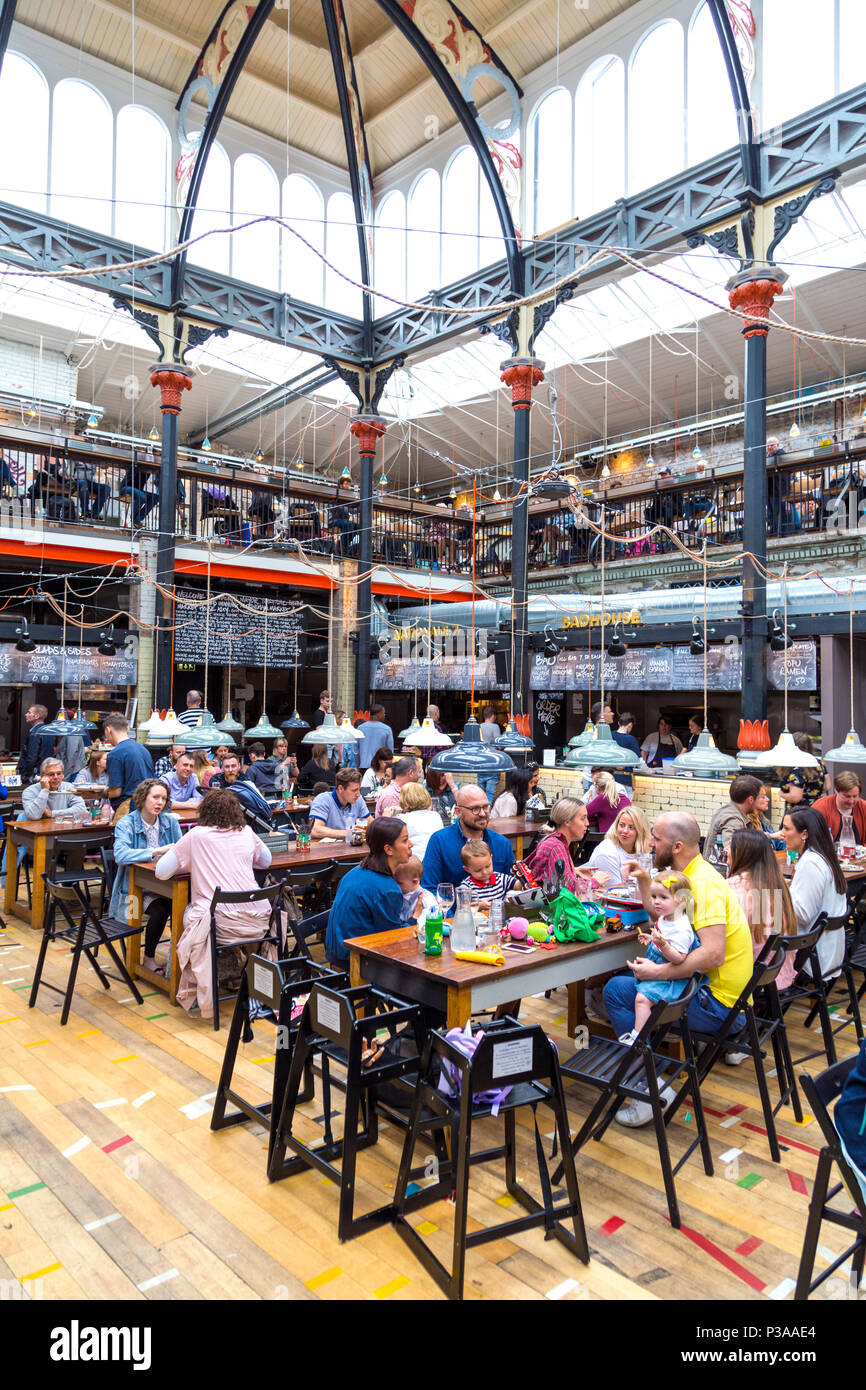 Les gens de manger dans un food court, intérieur de Mackie maire à l'intérieur d'un ancien marché aux viandes à Manchester, UK Banque D'Images