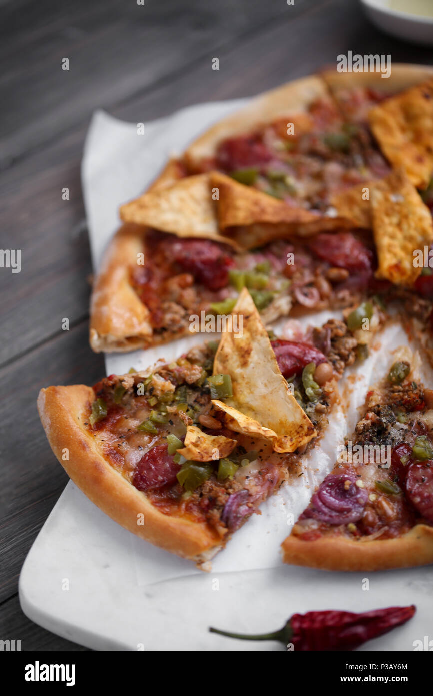 Pizza italien frais. La photographie alimentaire pour la conception. Pizza mexicaine avec les morceaux, l'oignon, piment jalapeno chaud sur une fine couche de pâte classique. Photo gros plan de coupe. Banque D'Images