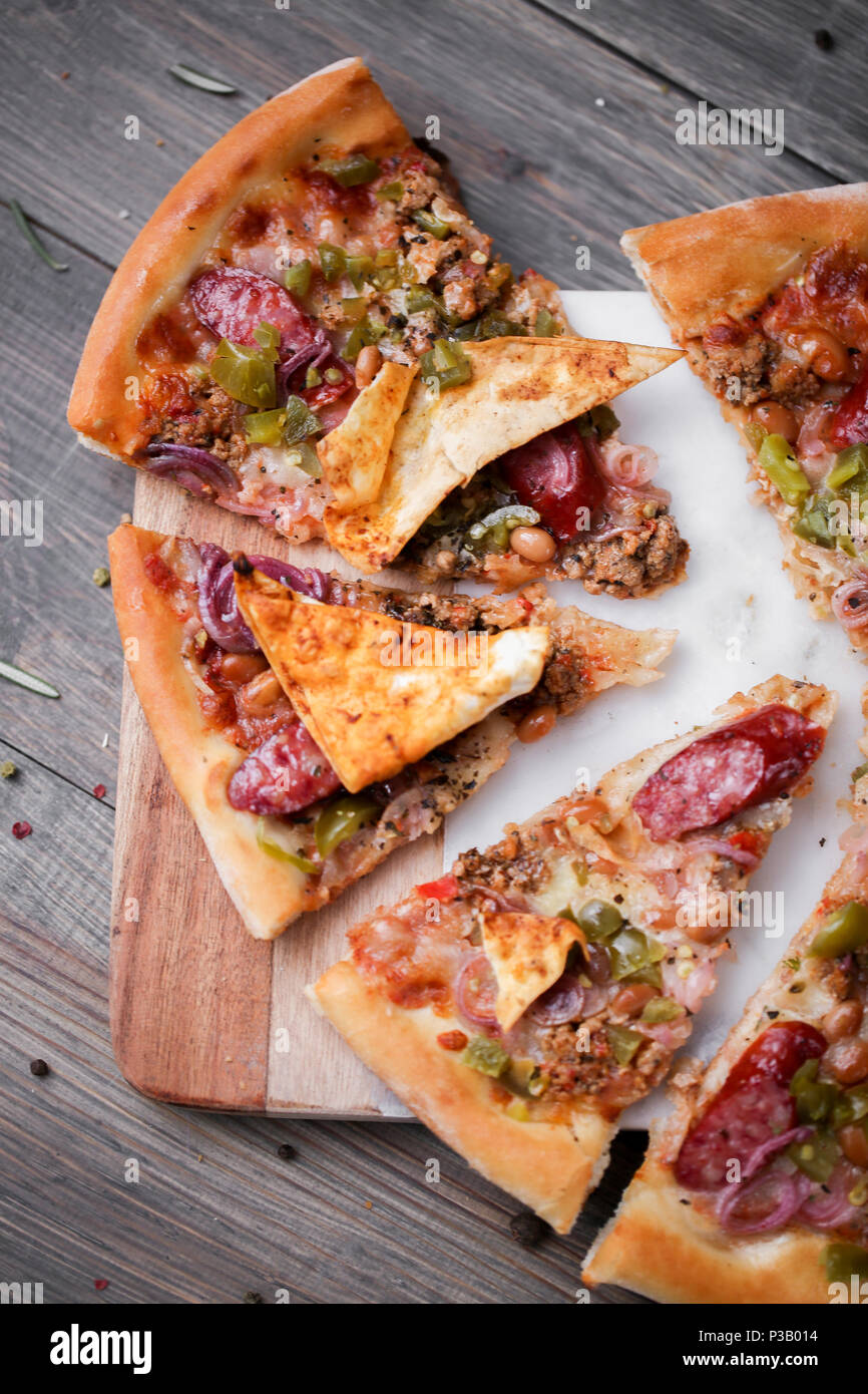 Pizza italien frais. La photographie alimentaire pour la conception. Pizza mexicaine avec les morceaux, l'oignon, piment jalapeno chaud sur une fine couche de pâte classique. Photo gros plan de coupe. Banque D'Images