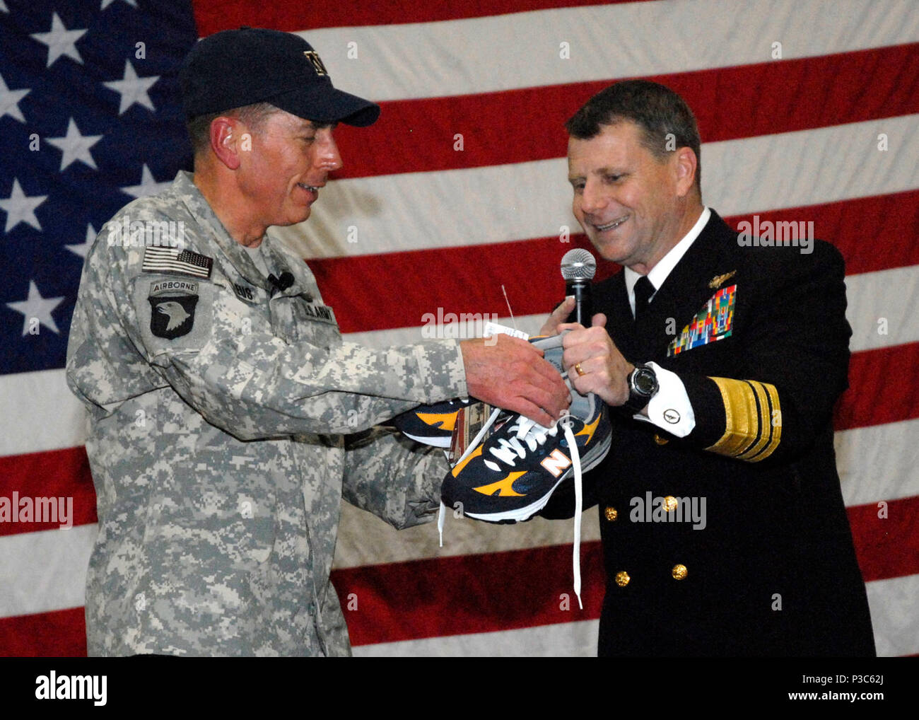 La Marine américaine Vice Adm. Bill Gortney, droite, le commandant de l'U.S. Naval Forces Central Command, l'Armée présente le Général David H. Petraeus, commandant du Commandement central des États-Unis, avec une paire d'or bleu marine et des chaussures de course à la base navale américaine de Bahreïn à Manama, Bahreïn, le 13 décembre 2009. Petraeus a été présenté les chaussures après l'académie navale des États-Unis battre le U.S. Military Academy de West Point au cours de la 110e match de football de l'Armée/marine la nuit avant. (DoD Banque D'Images