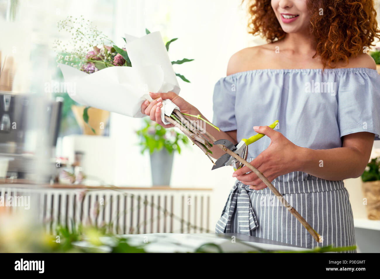 Cheerful nice woman cutting une succursale Banque D'Images
